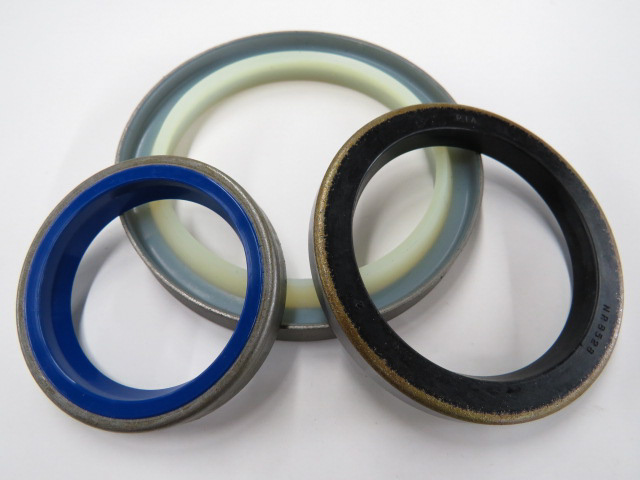 Metal-clad (canned) wiper seals with elastomer wiping lips in blue, black, and translucent materials, shown in multiple sizes on a white background.