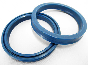 Two blue U-cup seals positioned on a light surface, showing their circular shape and U-shaped sealing lip profile, commonly used for hydraulic and pneumatic sealing applications.